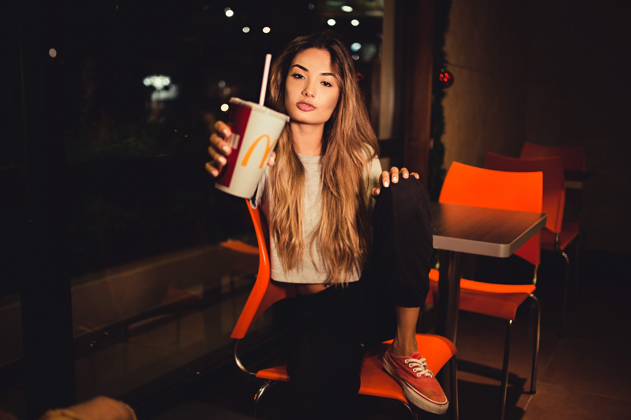 woman-holding-mcdonalds-cup-while-sitting-on-chair-1883305